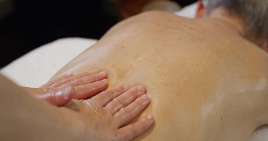 Female masseur massages blonde womans back at spa center