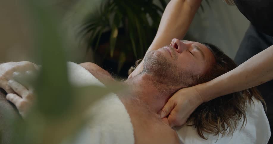 Female masseur massages mans shoulders at spa center