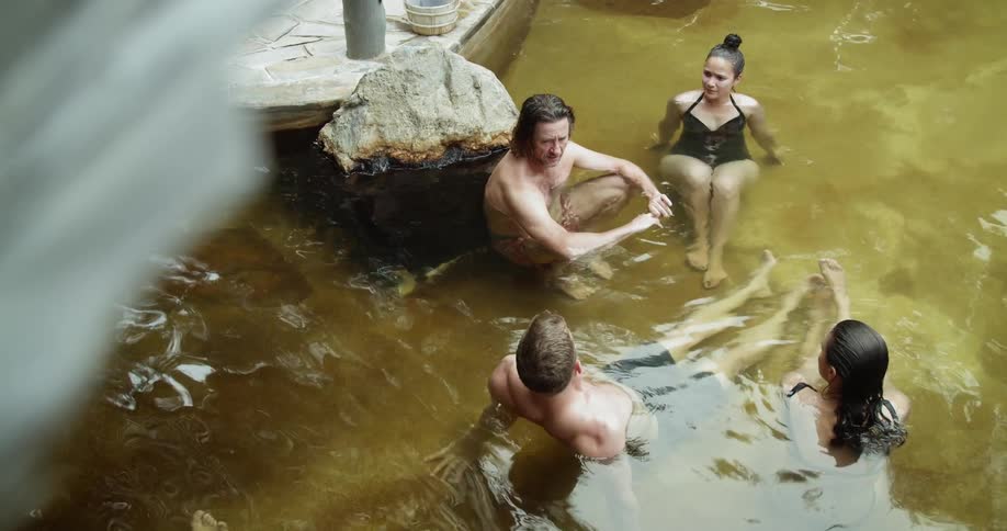 Two couples sit in a shallow pool talking