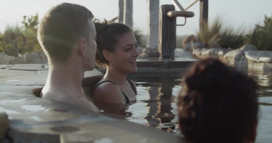 A group of people relaxing in a kind of thermal bath surrounded by trees