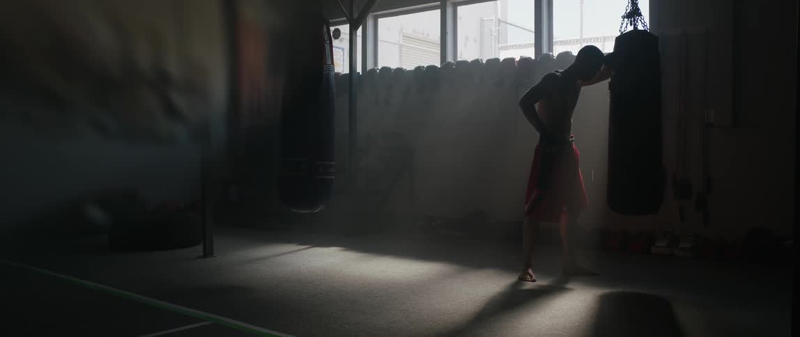 Man stands leaning against a punching bag