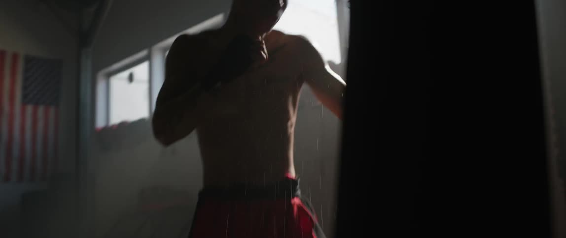A young man practices punching and jabbing on a punching bag in a gym