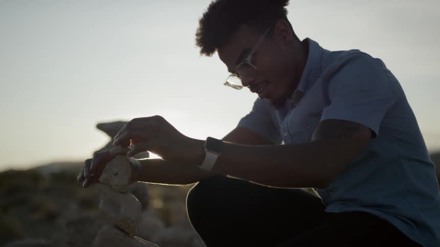 Black male stacking rocks