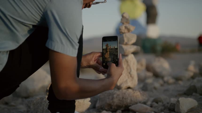 A man taking a photo of a rock monument