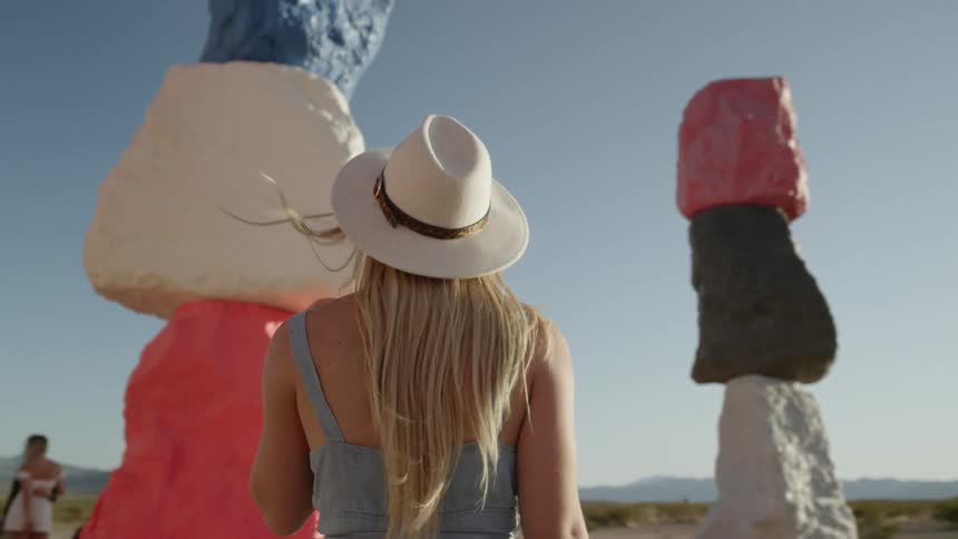 A woman studies large brightly painted boulders in the desert