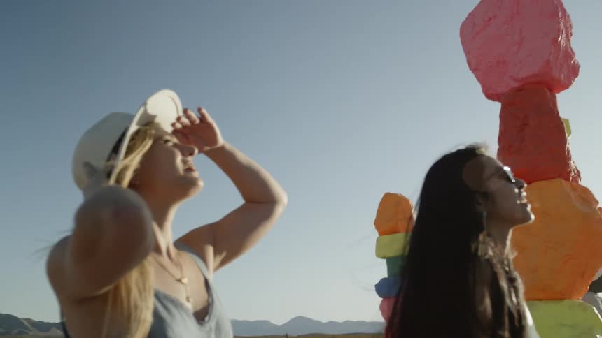 Women look up at colorful stacked boulders