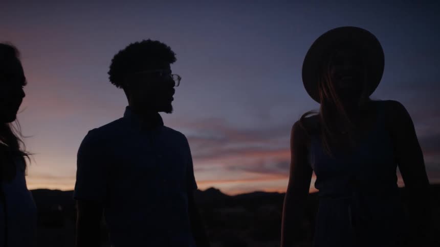 A group of friends are outdoors at sunset