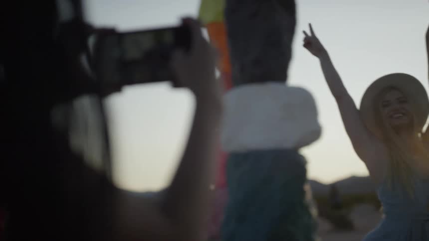 A young woman takes a picture of her friend who poses for her