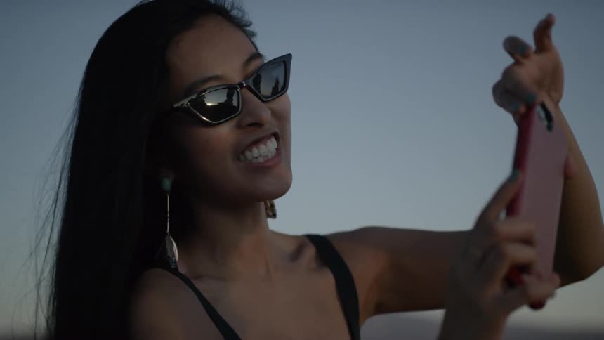 Asian woman laughing taking a selfie outdoors