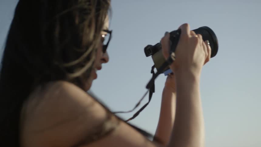 A woman holds a professional camera to take a picture