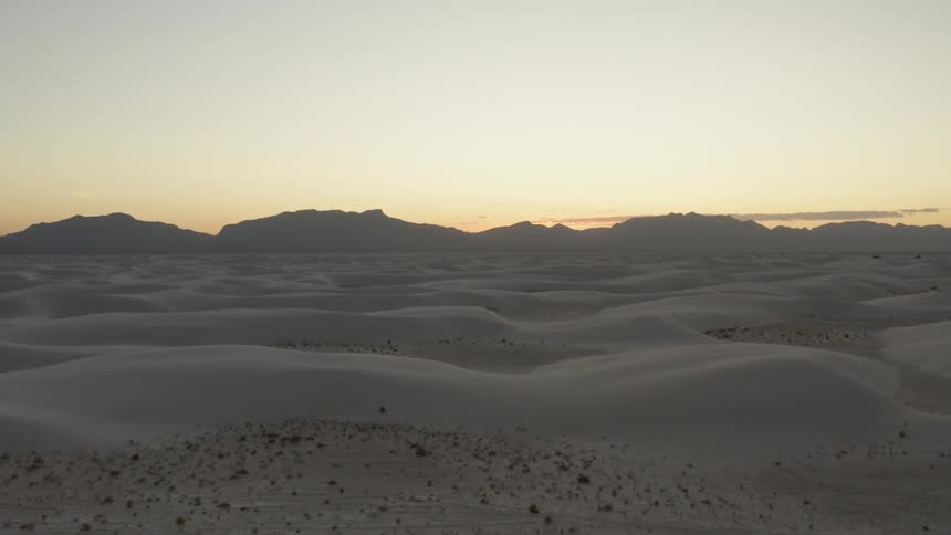 A desert area and sand is displayed while the sun is setting in the horizon