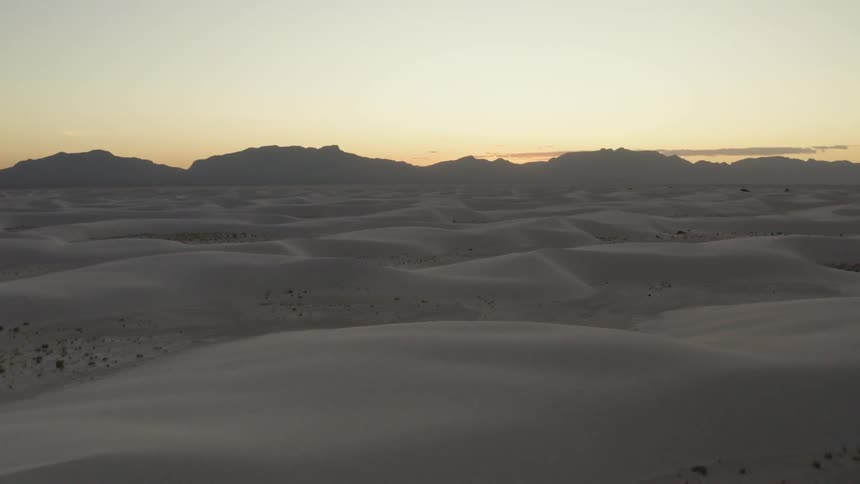 The sun sets over the sand dunes