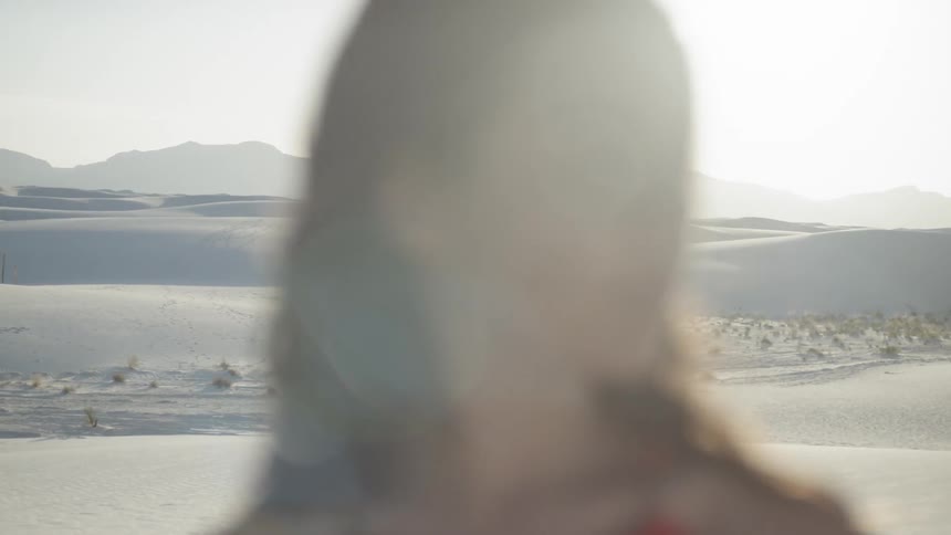 Brunette woman looks sideways while the sun goes down in the desert