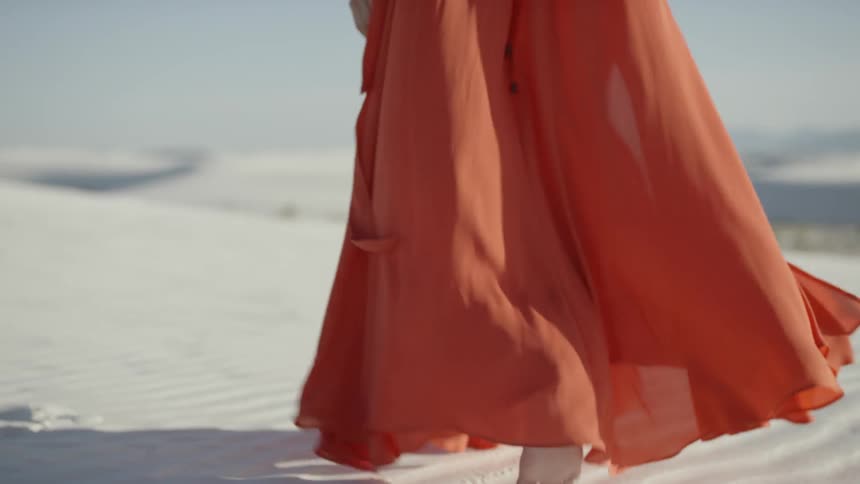 A woman is walking on the beach that is covered in sand