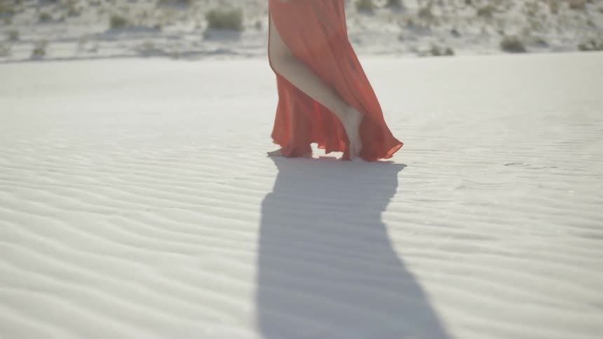 A woman walks through the sand
