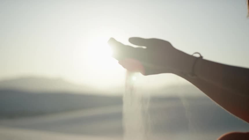 A young woman lets sand run through her hands