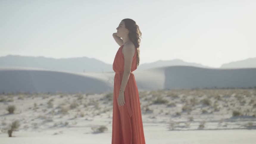 A woman in a dress stands in the desert