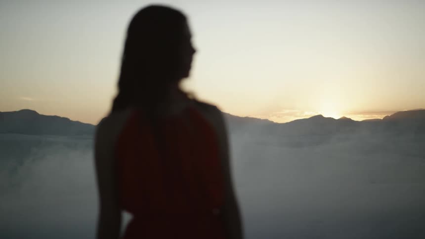 A woman turns around in the desert wearing a red dress