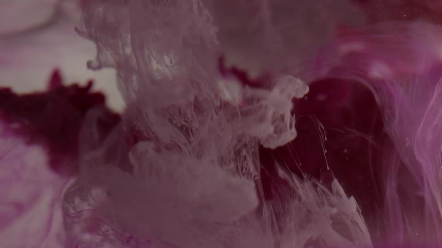 Purple paint shoots through liquid and swirls and blends with clouds of white