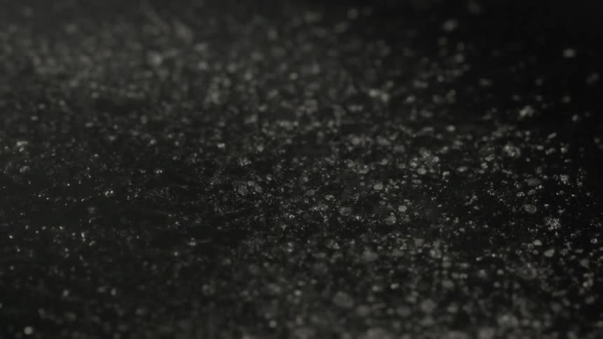Water spray on to a dark surface and bubbles form