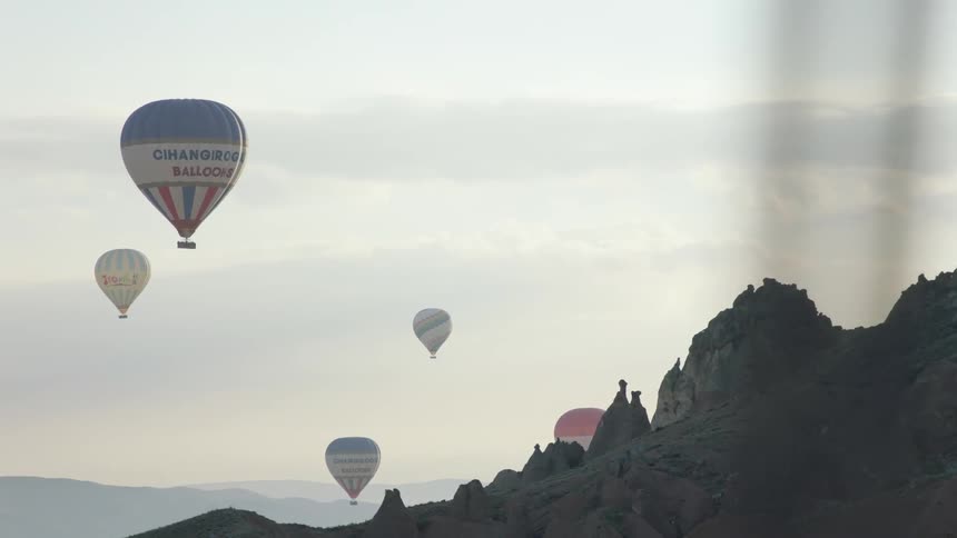 The hot air balloons travel over the mountains
