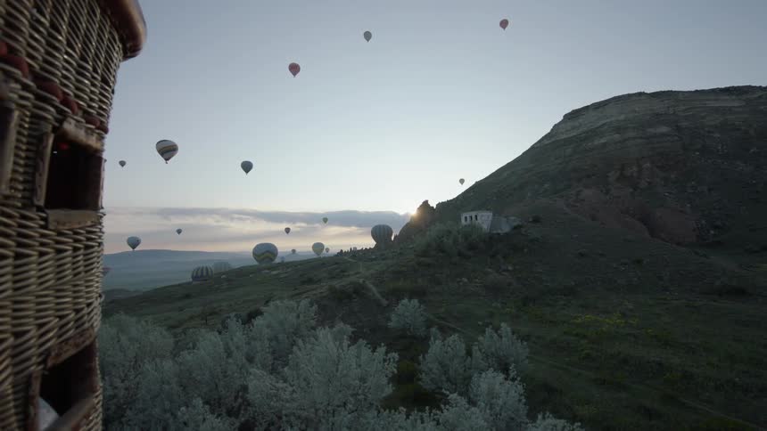 Hot air balloons are coming down in the horizon