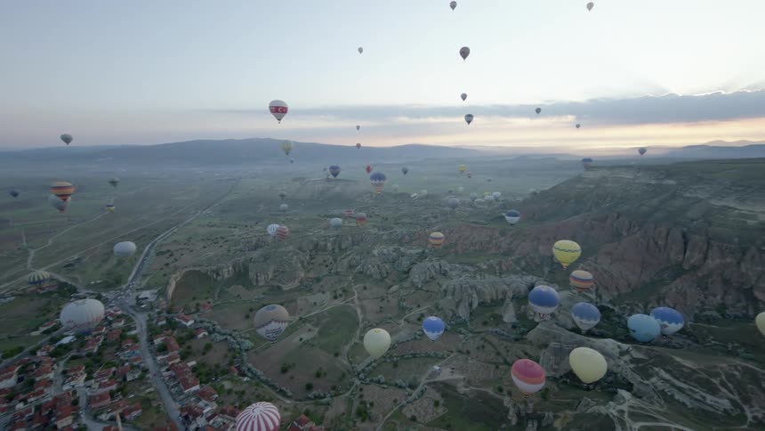 Hot air balloons floating over a neighborhood with mountains and the sky in the background