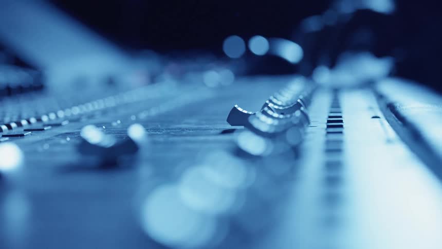 A audio specialist moving sliders on an audio mixing board
