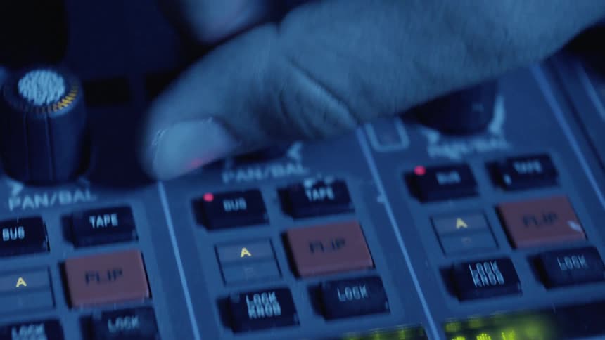 A person moves dials on a mixing board