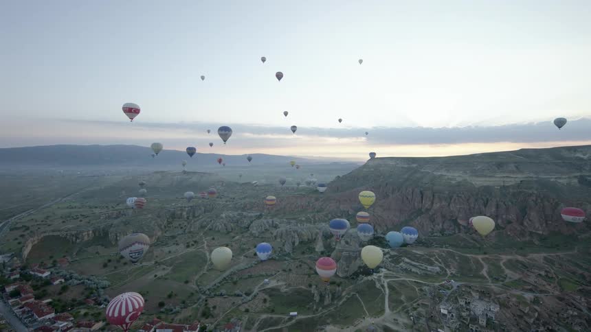 Wide shot of hot air balloons over a town