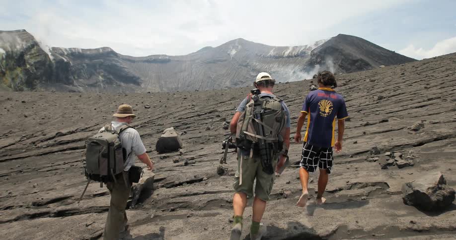 Guys walking across a volcano with camera equipment