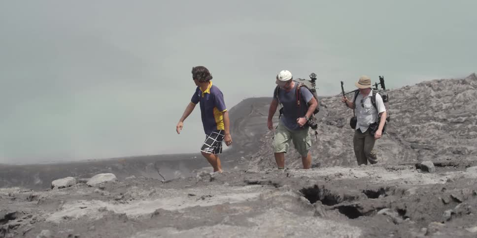 People are hiking over a mountain on a cloudy day