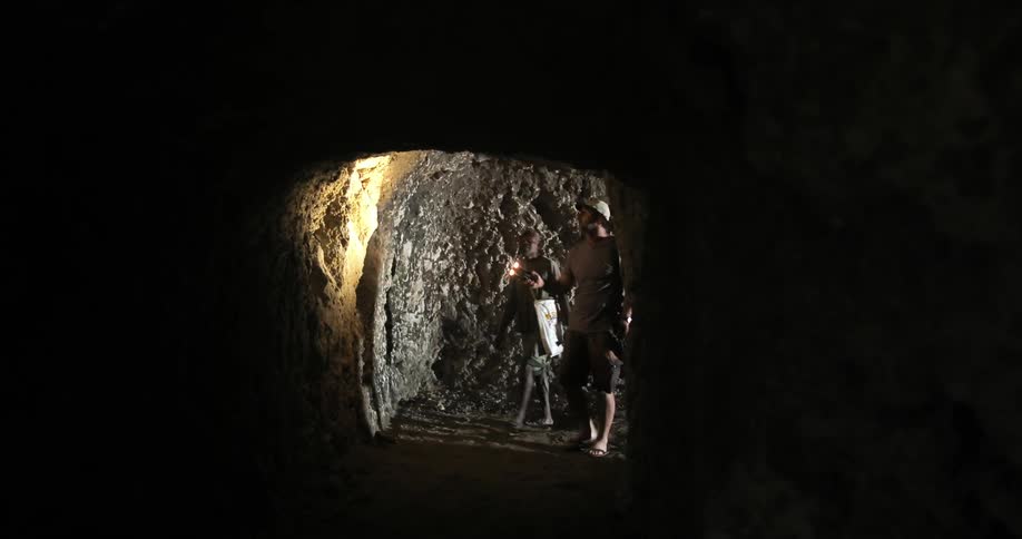 Explorers Walking Through Cave