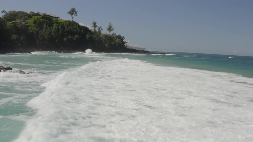 Roiling waves crash to the shore of a rugged coastline