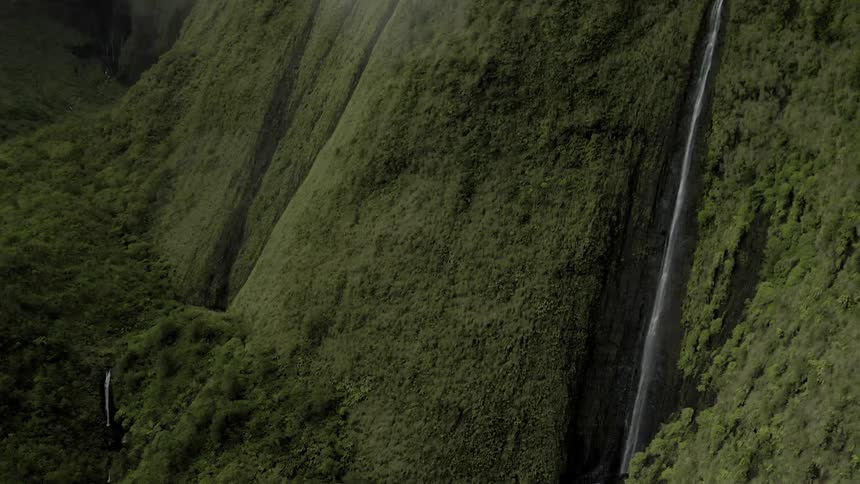 A narrow waterfall plunges down a steep cliff