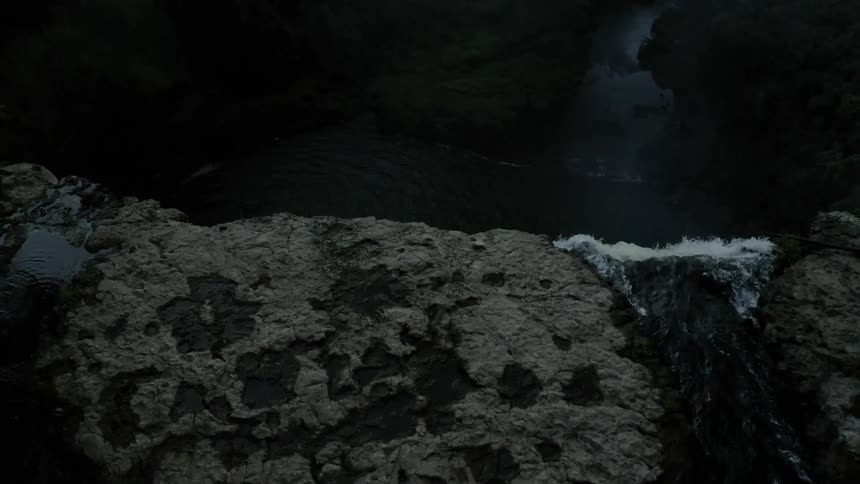 Water is pouring down a cliff into a river
