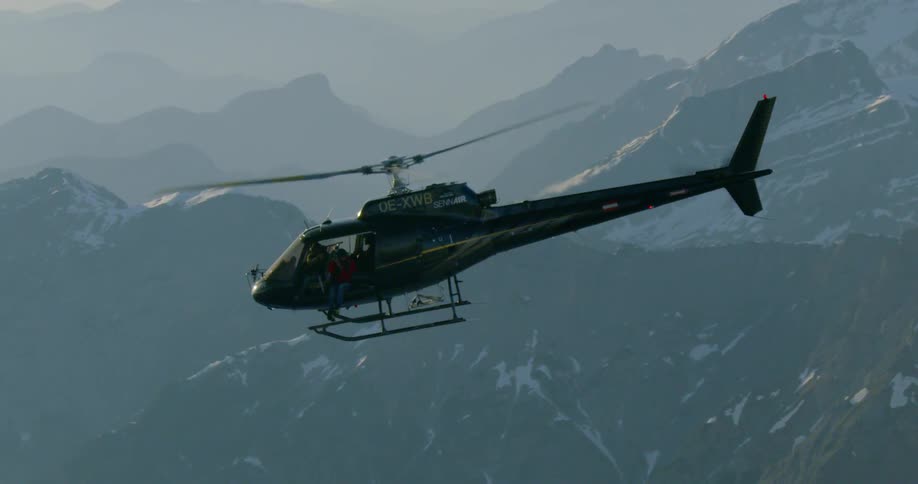 A helicopter flying over snowy mountains