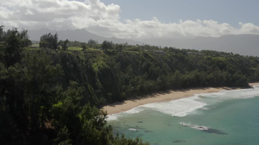 A beach below cliffs covered in greenery