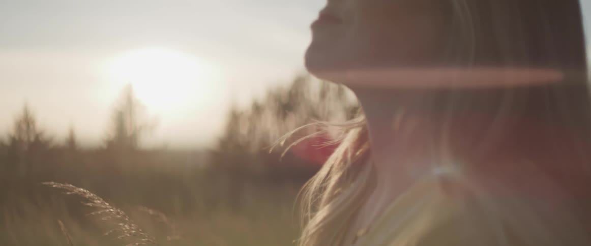 A woman looking up at the sky while among tall grass