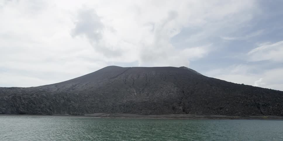 Water flowing in front of a mountain on a cloudy day
