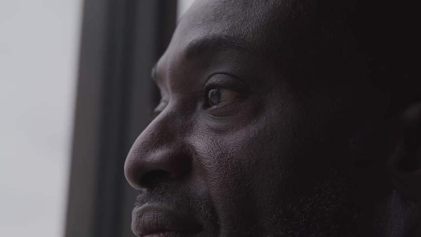 Black man stares out a window