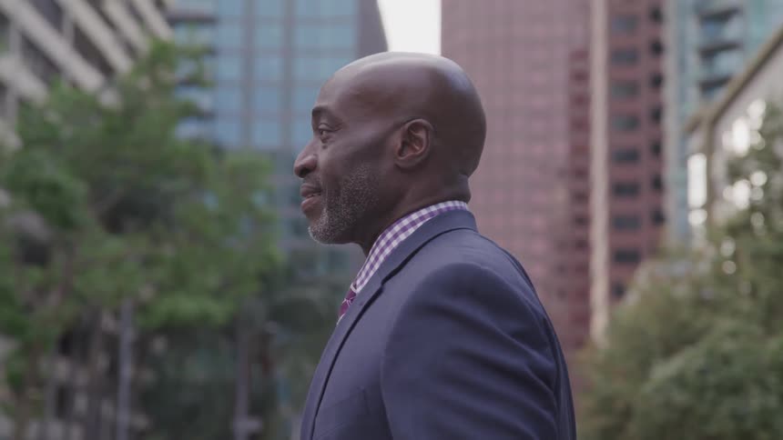A black man in a suit walks outside