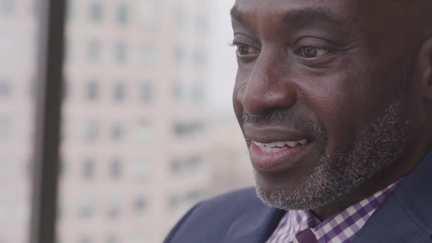 Black businessman uses laptop excitingly in the office