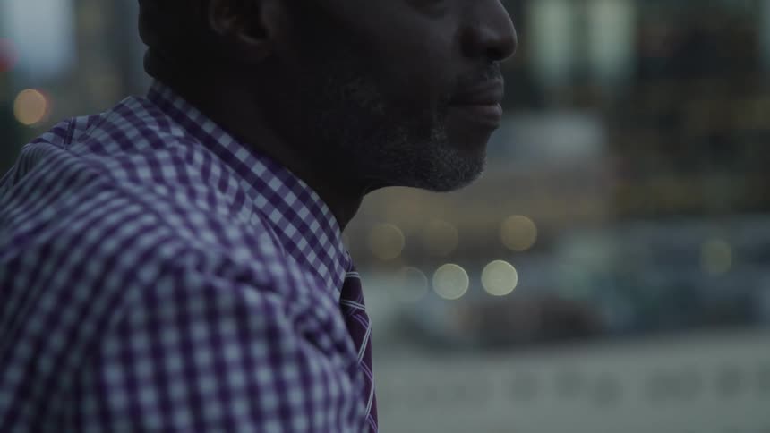 Older man looks out onto city in early evening