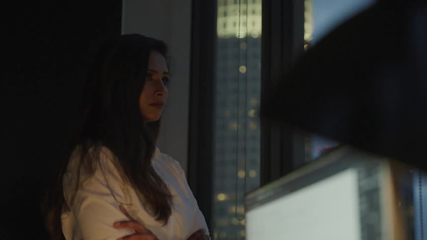 A woman is in a building and staring out a window