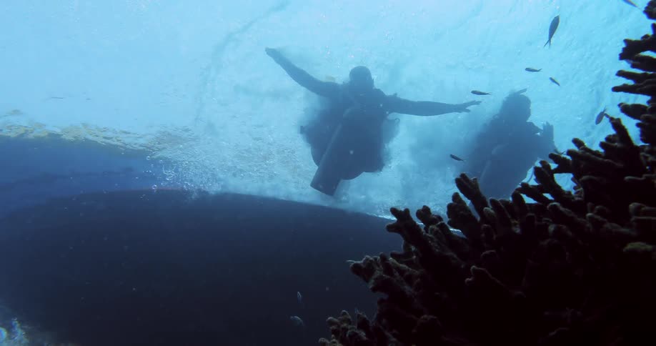 Divers jump from a boat into the ocean