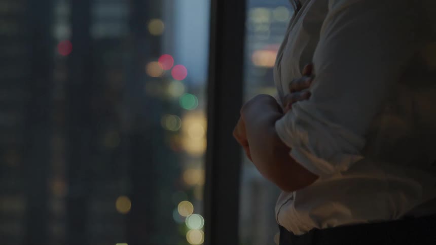 A woman standing with her hands cross staring out of a window