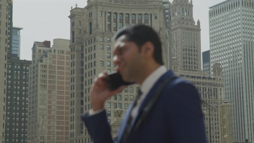 A man talks on his cellphone while outside on a rooftop in the city