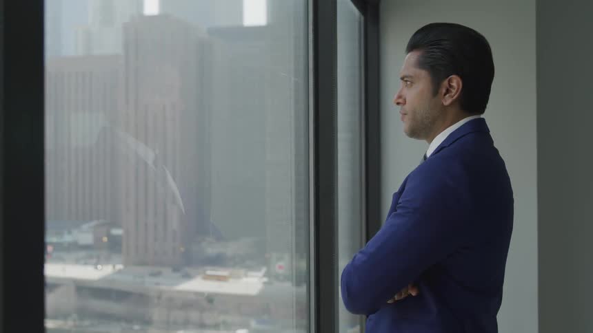 Man with suit staring at the outside of window