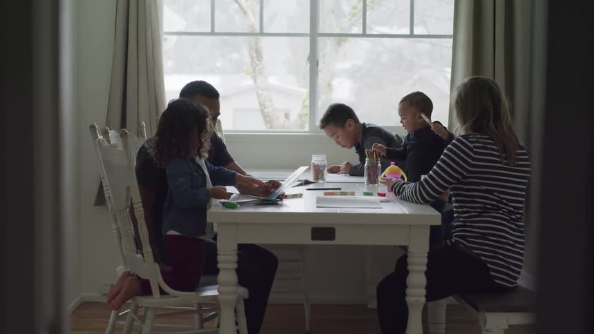 A family sits together at a dining table doing crafts